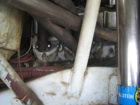 1990 Ford Bronco - close-up of a race vehicle engine bay with exhaust headers, roll-cage tubing and a Bilstein sticker.
