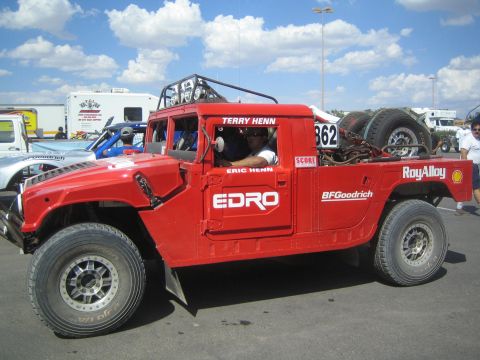1990 Ford Bronco - red Hummer-style off-road race vehicle number 862 covered in EDRO, RoyAlloy and BFGoodrich sponsor decals sits in a sunny paddock.