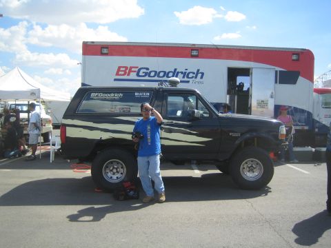 1990 Ford Bronco - black lifted Ford SUV on large off-road tires parked in front of a BFGoodrich Tires support trailer, with a person standing in front.