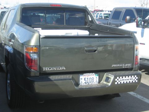 1990 Ford Bronco - rear tailgate of a dark olive-green Honda Ridgeline 4WD pickup showing a checkered Checkers decal and an Arizona license plate.
