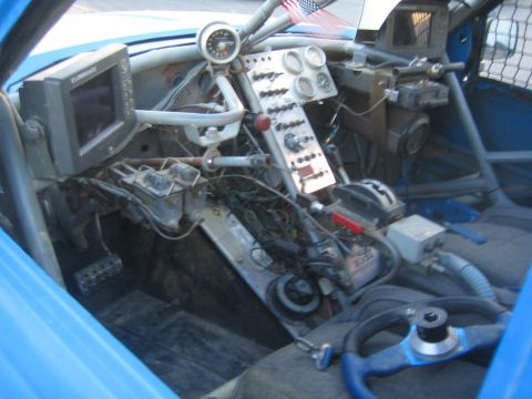 1990 Ford Bronco - Stripped interior of a blue off-road race truck showing the dash panel, gauges, GPS unit and roll cage.