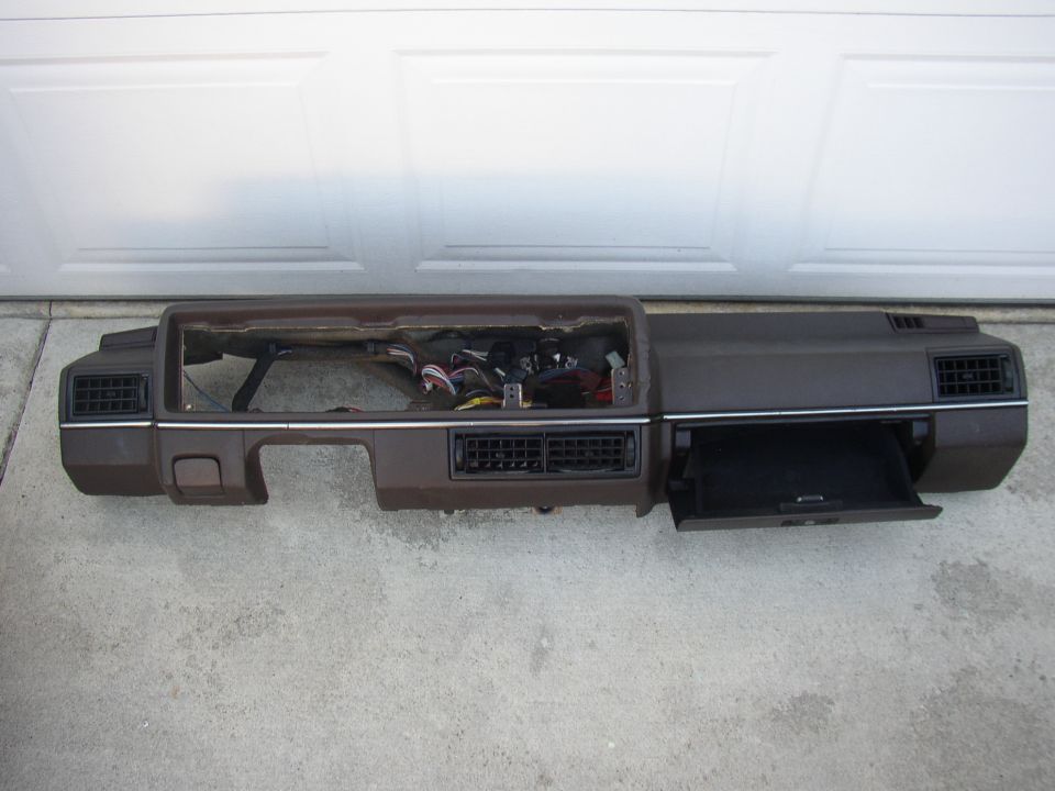 Brown dashboard assembly with vents and glovebox removed from vehicle, on driveway