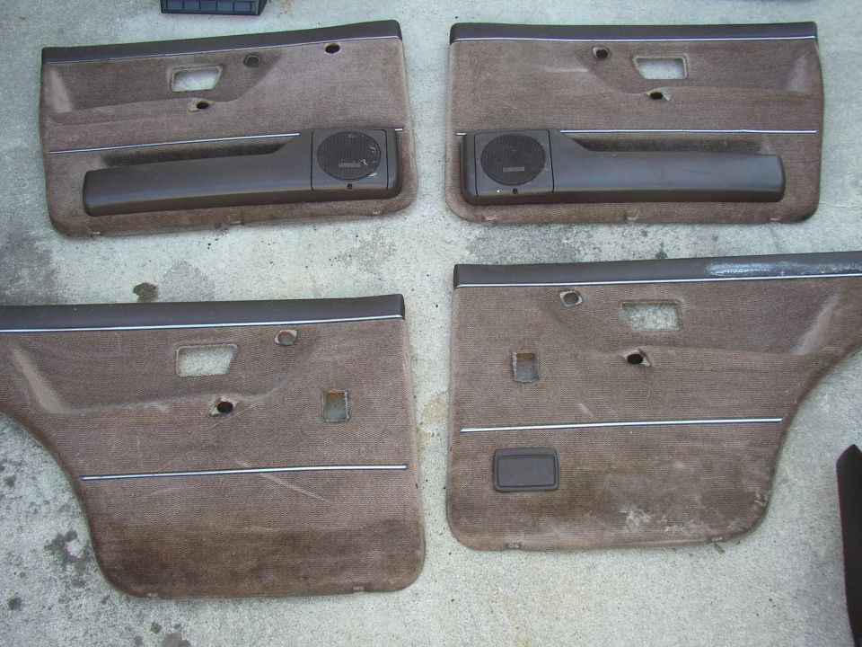 Four brown cloth door panels with speaker grilles laid out on concrete floor