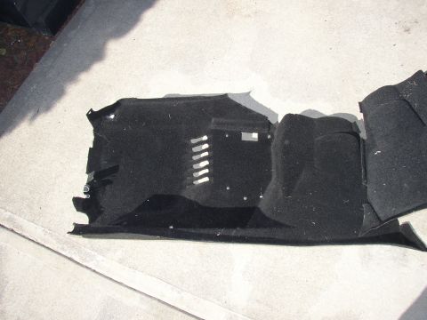 1987 Volkswagen Golf - This black carpet piece appears to be from the floor of a vehicle, showing molded contours and attachment points.