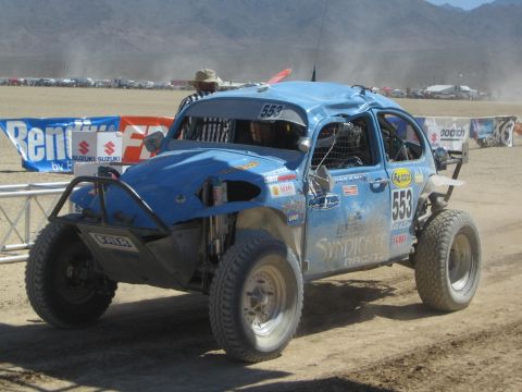 1990 Ford Bronco - blue Volkswagen Beetle-bodied off-road race buggy marked number 553 kicks up dust on a desert race course.
