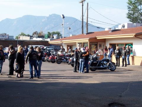 1972 Ford Ranchero - A gathering of people and motorcycles in front of a building, with a mountain range visible in the distance.