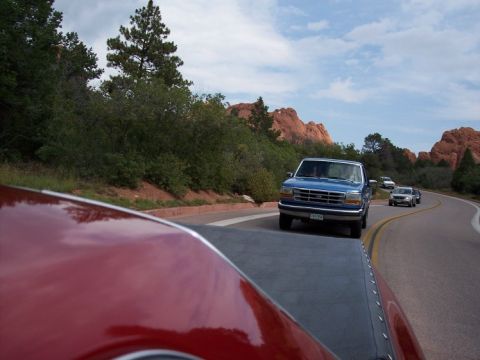 1972 Ford Ranchero - A red vehicle is on the road, with a white van driving ahead on a clear day.