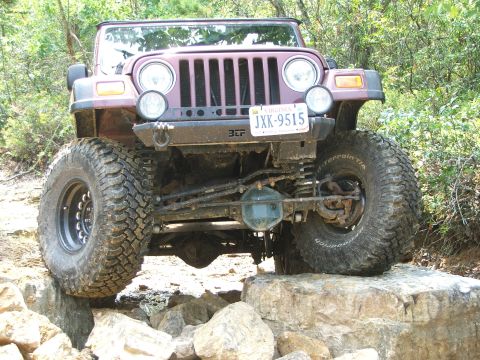 1996 Ford Bronco - A maroon Jeep Wrangler TJ navigates a rocky trail, its off-road capabilities.