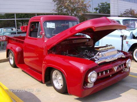 1970 Ford Ranchero - This red 1956 Ford F-100 pickup truck is displayed with its hood open, revealing the engine bay.