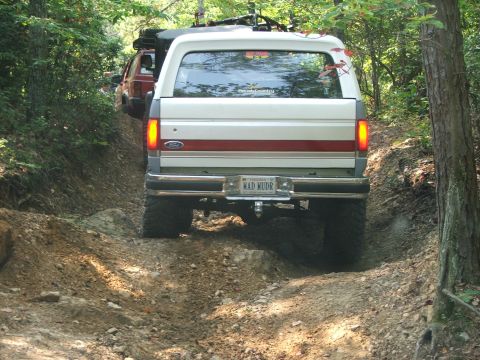 1996 Ford Bronco - 1996 Ford Bronco navigates a challenging off-road trail with another vehicle following.