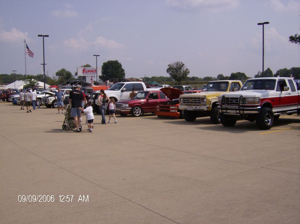 Line of trucks and cars parked in a lot, with a Summit tent in the background