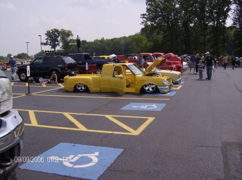 1970 Ford Ranchero - A yellow pickup truck is displayed with its doors and hood open at an outdoor event.
