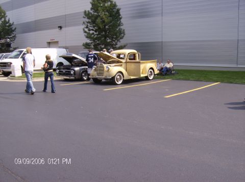 1970 Ford Ranchero - Two classic pickup trucks are parked in a lot outside a modern building.
