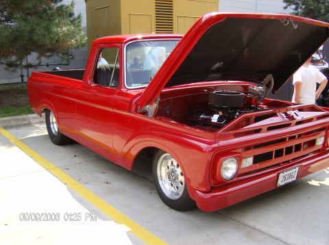 1970 Ford Ranchero - Red 1965 Ford F-100 pickup truck with custom wheels and lowered suspension, hood open.