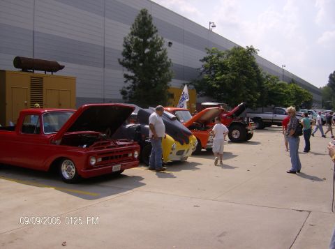 1970 Ford Ranchero - Several custom trucks are on display at an outdoor event, with people milling around.