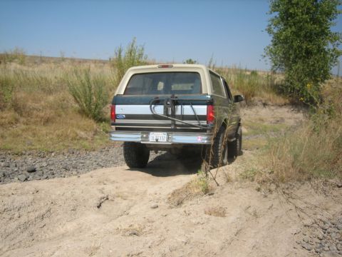 1995 Ford Bronco - Rear view of a 1995 Ford Bronco navigating a rough, unpaved trail.