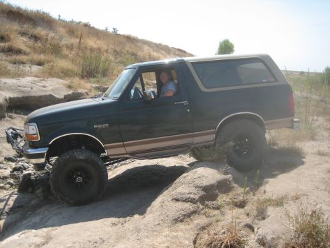 1995 Ford Bronco - A 1992 Ford Bronco navigates a rocky trail with a driver visible inside.