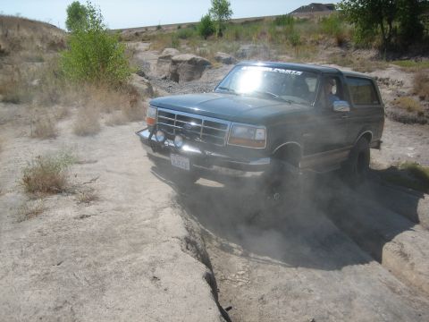1995 Ford Bronco - This 1995 Ford Bronco is shown navigating a challenging off-road course with dust kicking up around its tires.