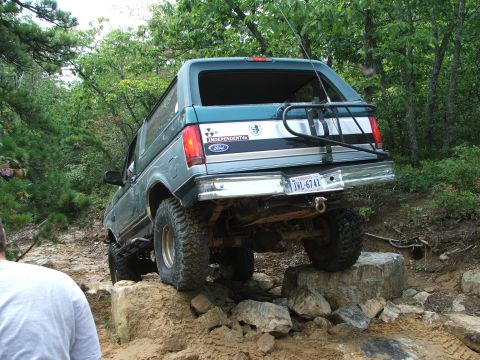 1996 Ford Bronco - A teal and silver 1996 Ford Bronco navigates a rocky trail with a bike rack attached.