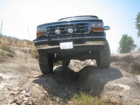 1995 Ford Bronco - This black Ford Bronco is shown from the front, tackling a challenging rock crawl course.