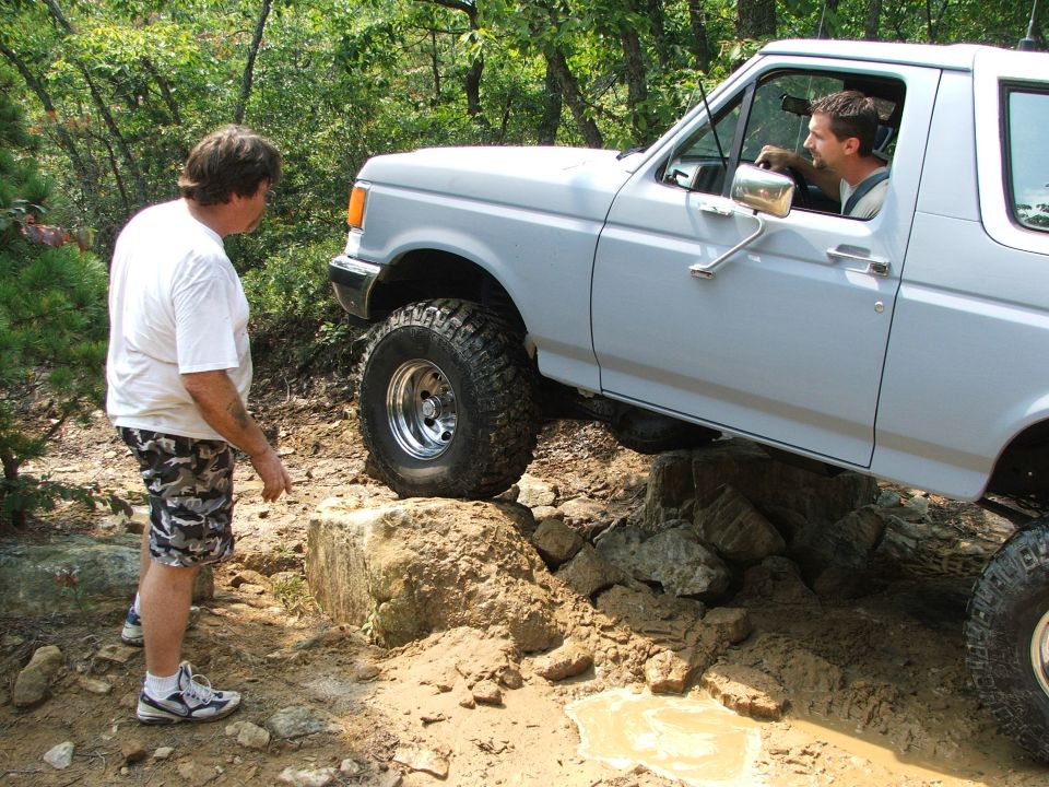 1996 Ford Bronco navigating rocky terrain with a person standing nearby