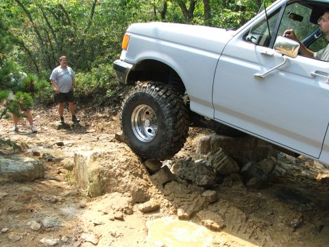 1996 Ford Bronco - A white pickup truck navigates a rocky off-road course with onlookers.