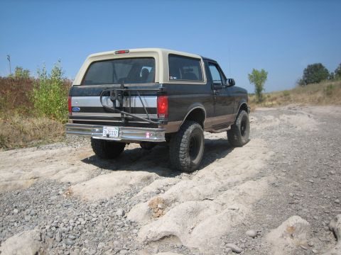 1995 Ford Bronco - This Ford Bronco is navigating a rough, off-road path under a clear blue sky.