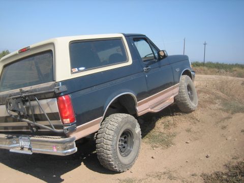 1995 Ford Bronco - This 1992 Ford Bronco is shown off-road with its tan removable top and large tires.