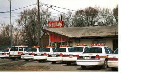 1999 Ford Crown Victoria - A line of 1999 Ford Crown Victoria police cars are parked outside a Donutland establishment.