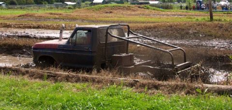 1979 Ford Bronco - Mud bogging event with a heavily modified pickup truck struggling through the mire.