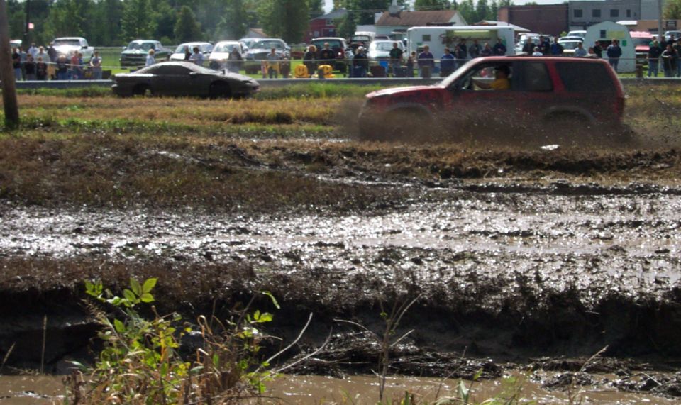 Red SUV splashing through mud pit