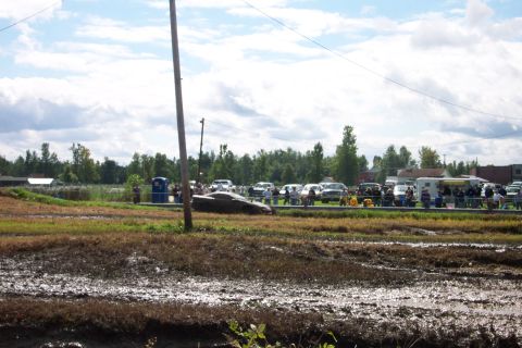 1979 Ford Bronco - Spectators and vehicles gather in a muddy field on a cloudy day.