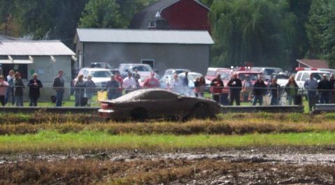 1979 Ford Bronco - A car is stuck in the mud during an event, with a crowd of onlookers in the background.