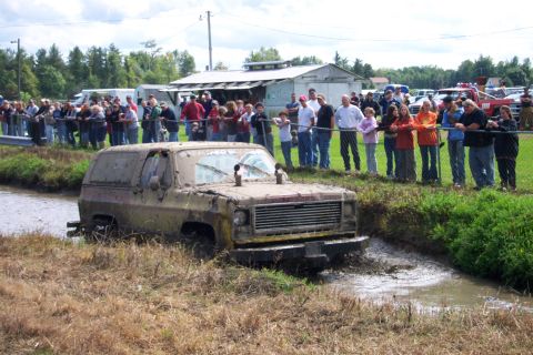 1979 Ford Bronco - A crowd watches as a heavily mud-caked 1975 Chevrolet K5 Blazer navigates a muddy ditch.