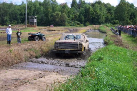 1979 Ford Bronco - A Chevrolet K5 Blazer navigates a muddy obstacle course with spectators watching.