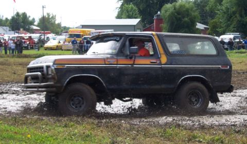 1979 Ford Bronco - A 1979 Ford Bronco navigates a muddy course, kicking up dirt as it goes.