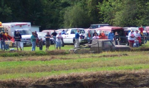 1979 Ford Bronco - Spectators watch as a truck is stuck in the mud during an event.