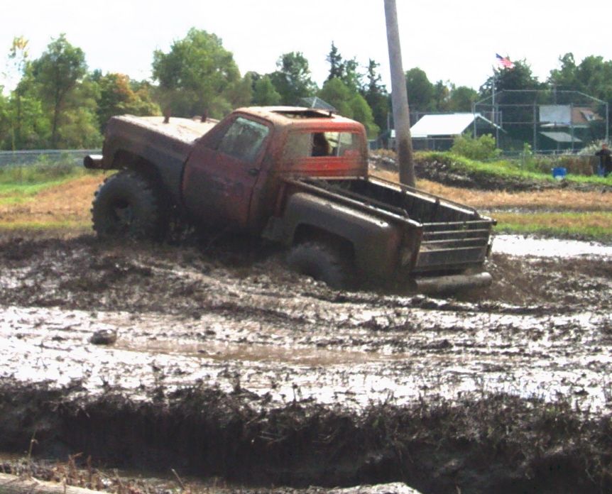 red pickup truck stuck in mud pit, sun roof open
