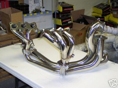 1995 Ford Probe - A shiny chrome exhaust manifold is displayed on a table, with storage boxes visible behind it.