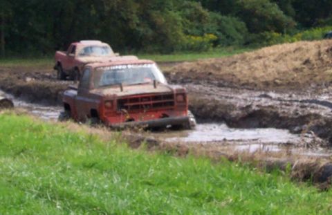 1979 Ford Bronco - Two trucks are stuck in the mud during an off-road event.