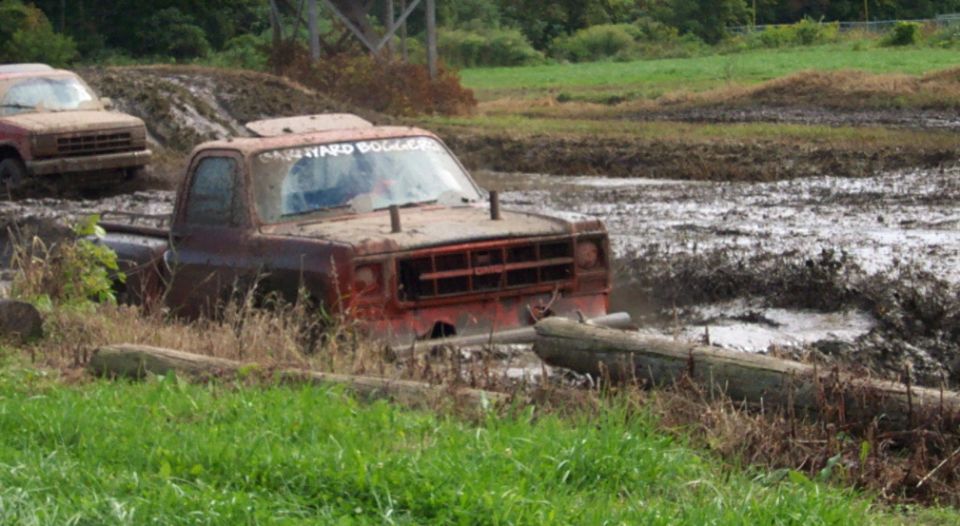Two trucks stuck in mud, one with 'HARD BOGGER' on windshield