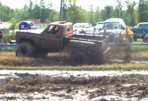 1979 Ford Bronco - Pickup truck participating in a mud bogging event with spectators watching.