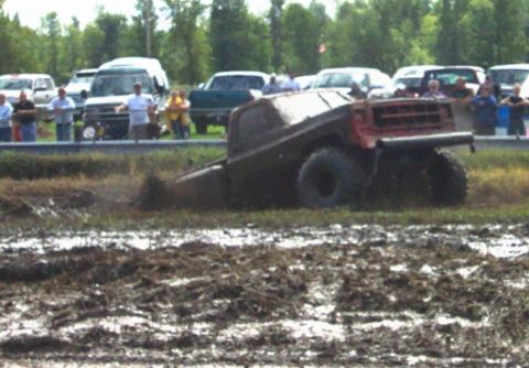 1979 Ford Bronco - A truck is stuck in the mud during a bogging event, with spectators in the background.