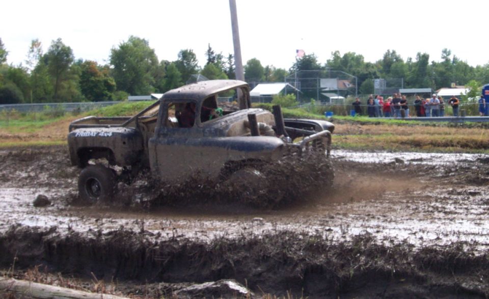 Mud-splattered pickup truck driving through a mud bog