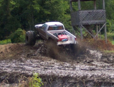 1979 Ford Bronco - A modified truck navigates a muddy obstacle course, demonstrating its off-road capabilities.