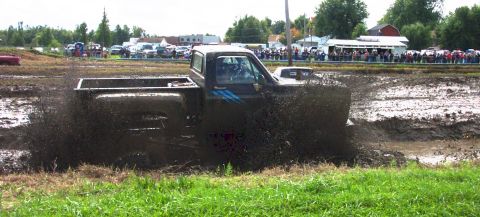 1979 Ford Bronco - A truck navigates a muddy track, kicking up a large spray of mud.