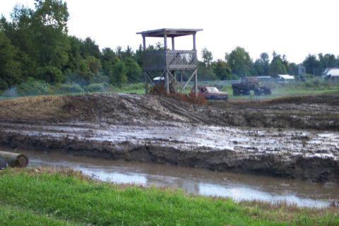 1979 Ford Bronco - Mud bog event with trucks and an observation tower in the background.