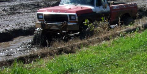 1979 Ford Bronco - This pickup truck is navigating a muddy terrain, with its front wheels deep in the mire.