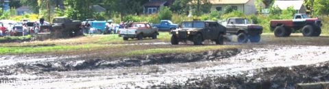 1979 Ford Bronco - Several vehicles, including trucks and an HMMWV, navigate a muddy terrain with onlookers present.