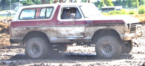 1979 Ford Bronco - A mud-covered 1978 Ford Bronco navigates a challenging off-road course.